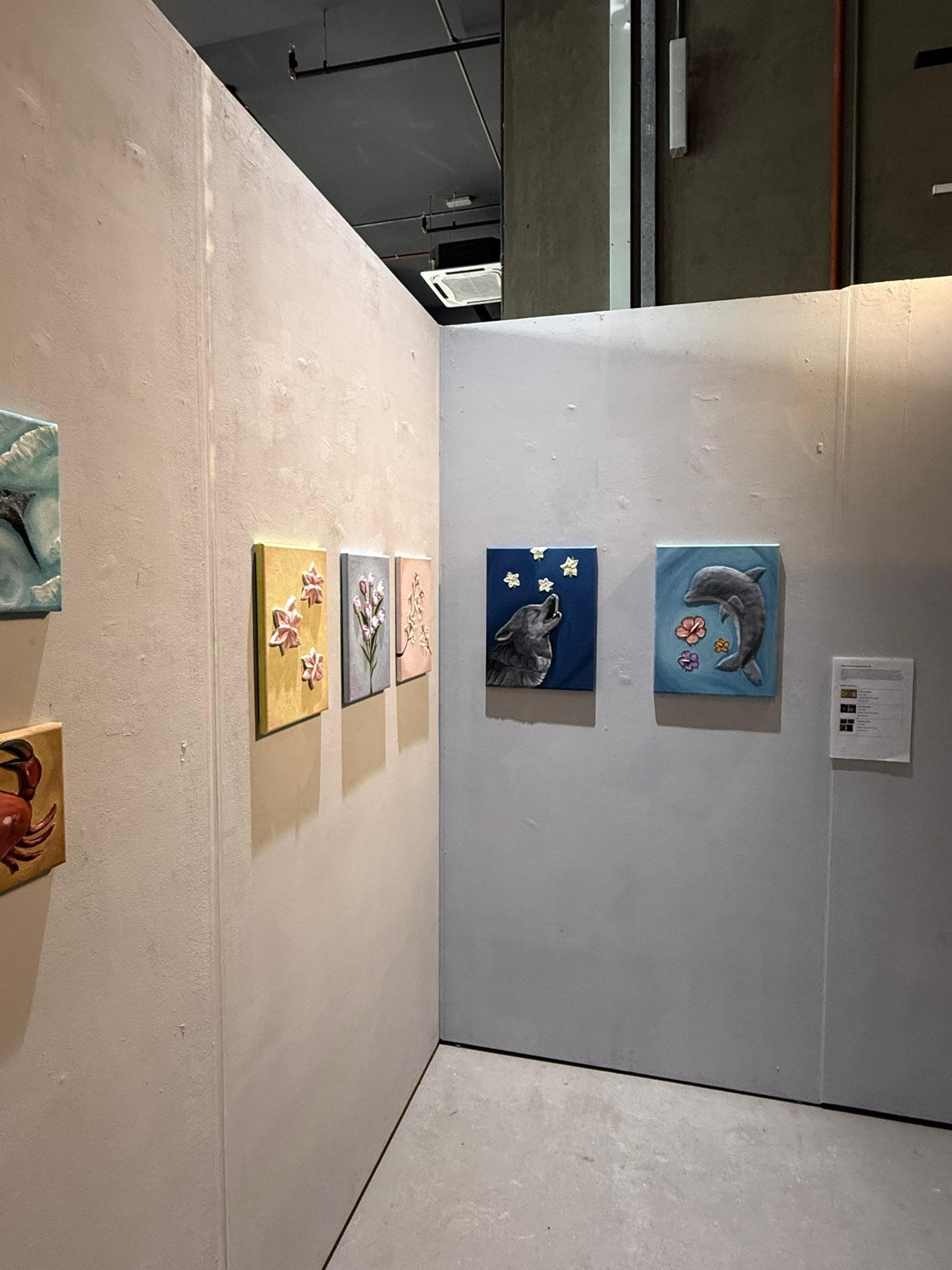 Dolphin and floral paintings displayed in the exhibition space